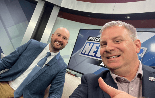thomas on a kbtk news set two males on a television news set with one holding a thumbs up
